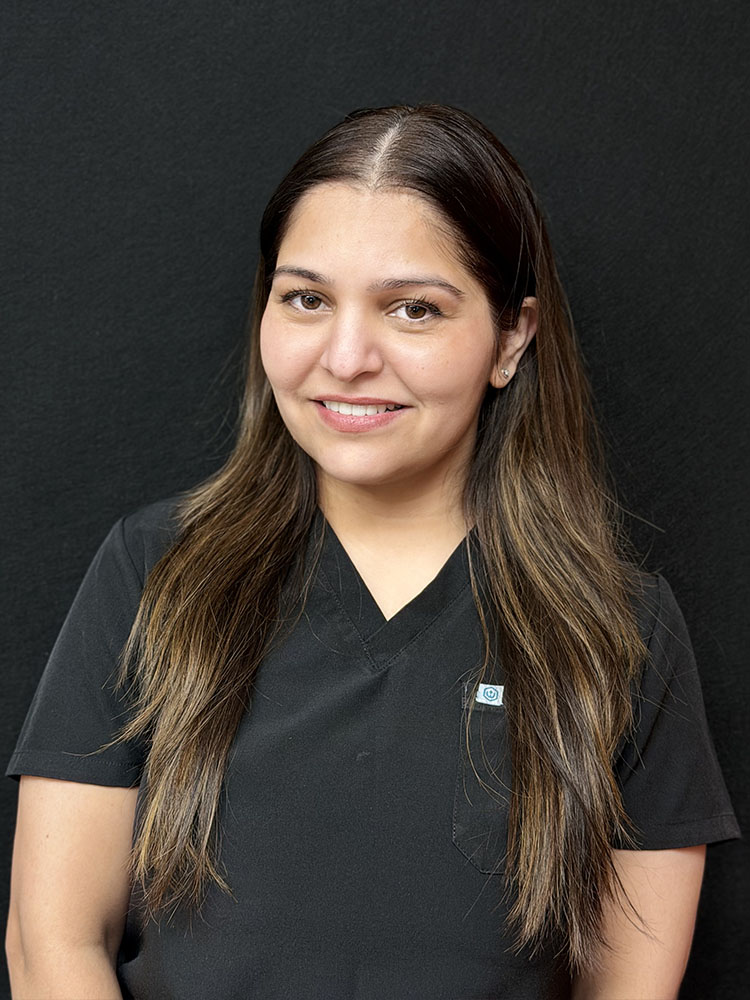The image shows a woman with long dark hair wearing a black shirt, posing for a portrait against a plain background.